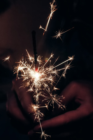 hand holding a burning sparkler bengal light. space for text. burning sparkler closeup in female hand in dark. happy new year and merry christmas concept. happy holidays, pyrotechnics conceptの写真素材