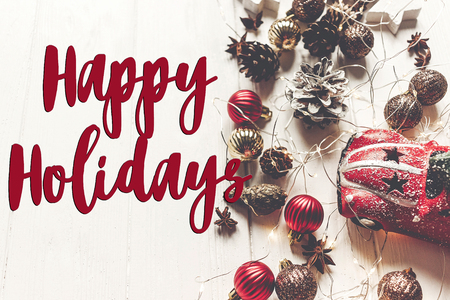 happy holidays text, seasonal greetings card sign. stylish toy car with tree and ornaments cones anise and lights on rustic white wood, top view, xmas cardの写真素材