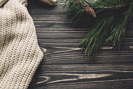 green fir branches and cozy warm knitted sweater top view, space for text. rustic christmas tree and woolen clothes on rustic wooden background. hygge winter imageの写真素材