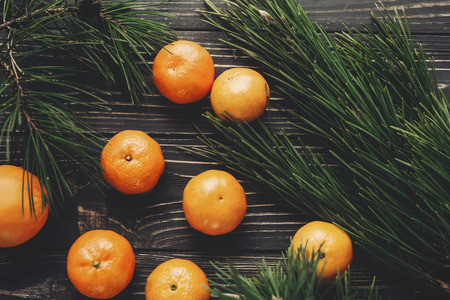 tangerines and fir branches on rustic wooden background top view. merry christmas, seasonal greetings, happy holidays. space for text. atmospheric momentsの写真素材