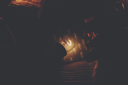 christmas concept. retro bulb lights and wooden tree toy on rustic wooden background top view in night. seasonal greeting card. space for text. atmospheric winter imageの写真素材