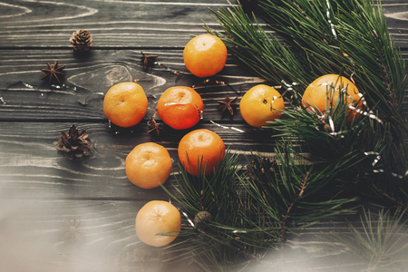 christmas flat lay. tangerines and fir branches anise and pine cones on rustic wooden background, top view. merry christmas, seasonal greetings, happy holidays. space for textの写真素材