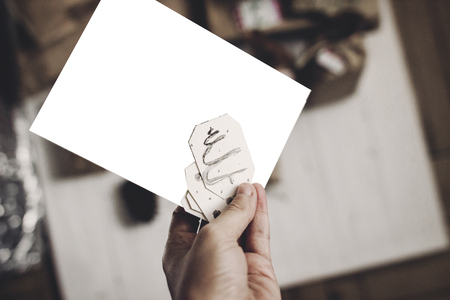 Hand holding Christmas card space for text, on white rustic woodenの写真素材