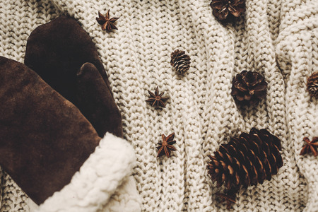 stylish christmas flat lay. gloves and pine cones anise on rustic knitted sweater background top view, space for text. atmospheric hygge winter image, seasonal greetingsの写真素材