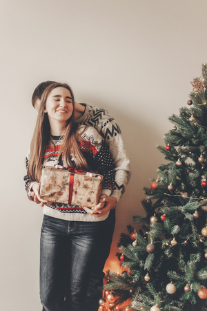 happy family in stylish sweaters exchanging gifts in festive room with christmas tree and lights. emotional moments. merry christmas and happy new year concept. happy holidaysの写真素材
