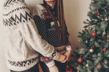 happy couple in stylish sweaters decorating christmas tree and embracing. merry christmas and happy new year concept. space for text.. family cozy momentsの写真素材