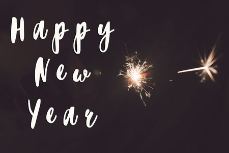 happy new year text sign, happy new year and merry christmas concept. hand holding burning sparkler firework bengal light. space for text. pyrotechnics concept, shining fire flame fireworks. happy holidays. tonedの写真素材
