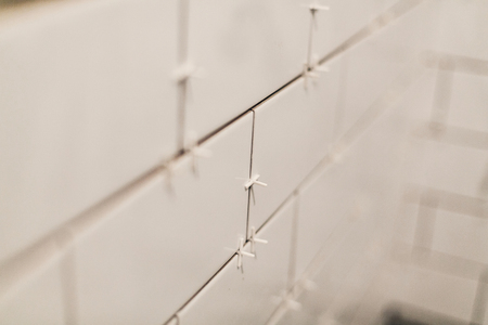 modern white tiles, renovation concept.  ceramic tiles  with spacers and grey cement walls in bathroom, renovating and working in toilet, space for text . repairingの写真素材