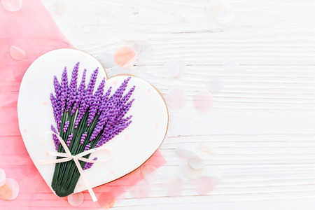 cookie heart with lavender bouquet on white rustic wooden background with confetti flat lay. happy mother's day greeting card. space for text . happy valentine's day or women's. mock-upの写真素材