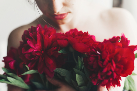 beautiful young woman holding red peoniesの写真素材