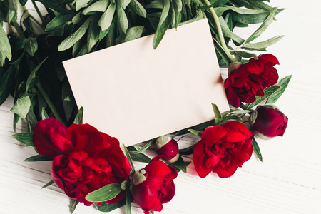 beautiful red peonies bouquet with craft paper on white wooden rustic background.の写真素材