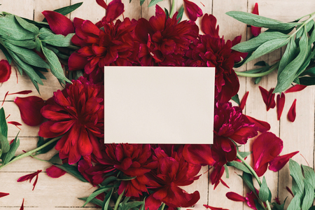 beautiful red peonies bouquet and craft paper card on white wooden rustic background, flat lay.の写真素材