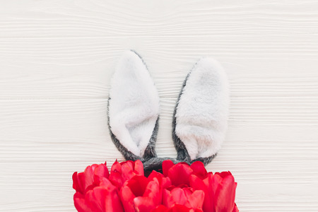 happy easter concept. bunny ears and stylish pink tulips on white wooden background flat lay with space for text. creative easter image. spring season's greeting card mock-upの写真素材
