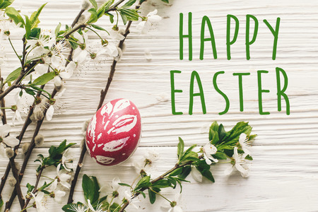happy easter text. season's greetings card. stylish Easter flat lay. painted egg on rustic wooden...