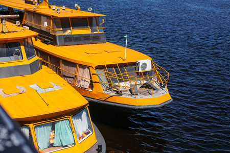 yellow boats in docks of city capital in sunny summer day. ship in blue waters on background of city buildings, pier with cargo and passengers marinasの写真素材