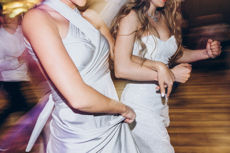 happy stylish bride and bridesmaids dancing and having fun at wedding reception in restaurant.の写真素材