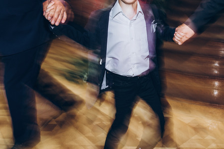 happy stylish people dancing and having fun at wedding reception in restaurant. guests dancing in light, people in motion at party in clubの写真素材