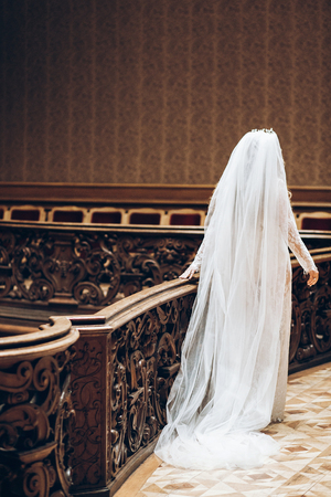 beautiful bride with long veil in lace robe, bridal boudoir in morning. back view. stylish woman in old room walkingの写真素材
