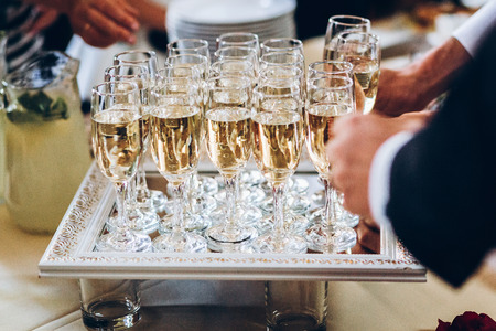 elegant people holding glasses of champagne at luxury wedding reception. hands taking drinks and toasting and cheering at social events. catering at christmas celebrationの写真素材