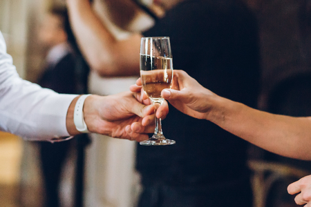 elegant people holding glasses of champagne at luxury wedding reception. hands taking drinks and toasting at social events.の写真素材