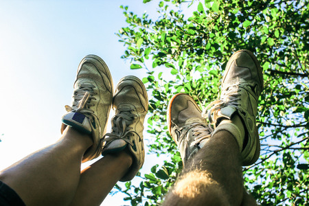legs of a couple on a summer picnic, having fun, on background of a sky