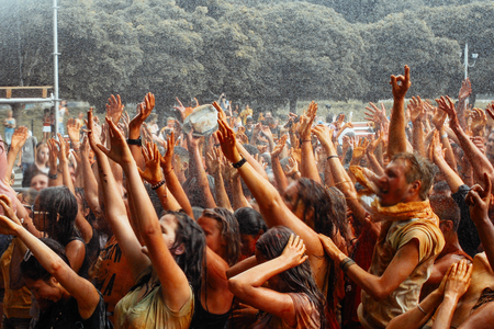 hands and happy people crowd partying under rain at holi fest, festival of colors in summer, amazing momentの写真素材