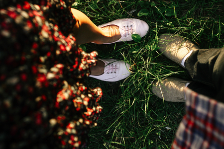 legs of happy stylish hipster on background of green grass in sunny summerの写真素材