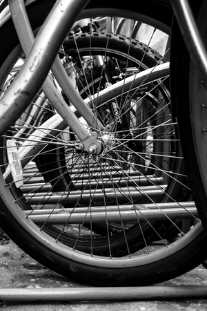 wheels of bicycles parked at rental station, black and white