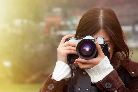 stylish happy girl traveler with photo camera on the background of sunny mountains taking photosの写真素材