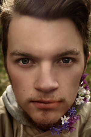 stylish blonde hipster with beard with flowers on the background of mountains