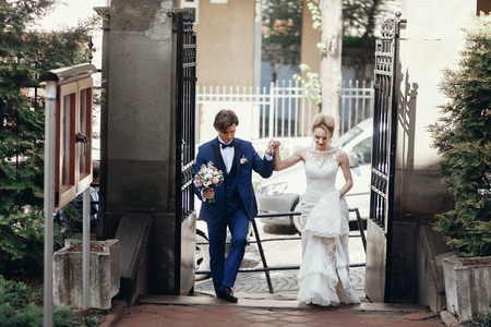 stylish groom and bride walking and holding hands in city street, hugging and embracing. wedding day concept. beautiful wedding couple, romantic moments elopmentの写真素材