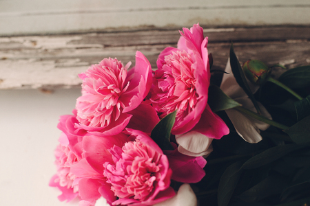 lovely pink peonies at rustic old white wooden window in light, space for text. top view. floral greeting card. happy mothers day or valentines. rural country image. shabby chic