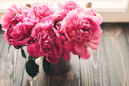 lovely pink peonies bouquet on rustic dark wooden background at window light, space for text. top view. floral greeting card. happy mothers day. spring image. shabby chic conceptの写真素材