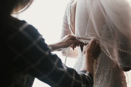 mother hands holding ribbons and helping dressing beautiful bride in morning. bridal getting ready in the morning. mom and daughter momentsの写真素材