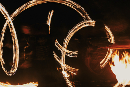 amazing fire show at night at festival or wedding party. Fire dancers swing, spinning fire and man juggling with bright sparks in the night. fire show performance and entertainmentの写真素材
