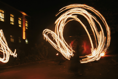 Fire dancers swing, spinning fire and man juggling with bright sparks in the night. fire show...