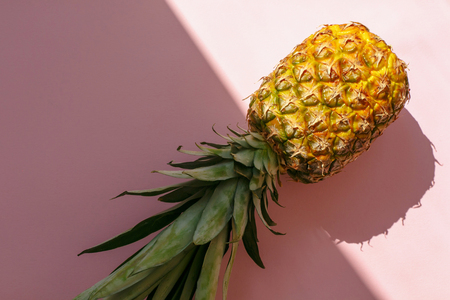 juicy pineapple on trendy pink paper background in sun light. flat lay. creative contrast summer image. vacation and party concept. space for text. summer holidaysの写真素材