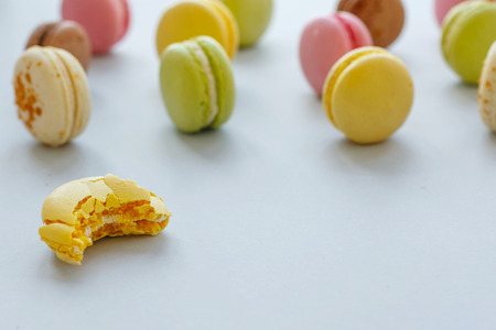 tasty bitten yellow, pink, green and brown macarons on trendy pastel gray paper. space for text. delicious colorful macaroons candy for party. yummy background. diet conceptの写真素材