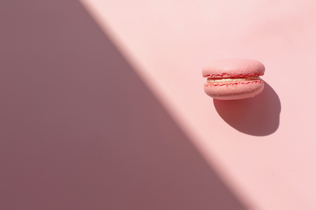 tasty pink macaron in sunny light on trendy pastel pink paper flat lay. space for text. pink macaroon in light contrast. modern food photography concept. minimalism conceptの写真素材