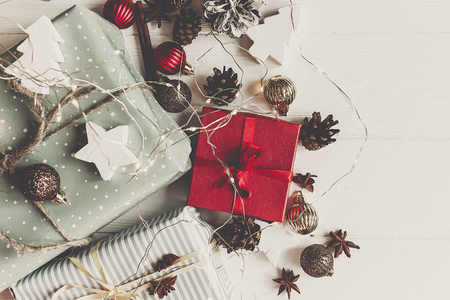 wrapped present boxes with ornaments pine cones anise on white wooden background with lights top view, space for text. christmas flat lay. seasonal greetings card. happy holidaysの写真素材