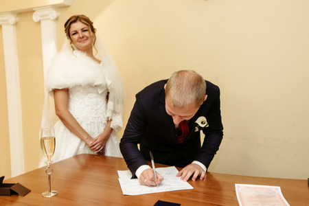 happy gorgeous bride and stylish groom signing official document wedding register, emotional moment, ceremonyの写真素材
