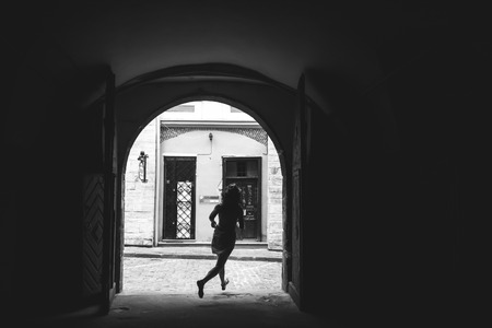 stylish woman hipster running and having fun on old european streets in sunny morning, black and white photoの写真素材