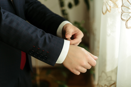 happy gorgeous handsome groom getting ready dressed in the morning on background of a room
