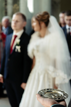 wedding ceremony of stylish elegant blonde bride and happy groom, putting on rings  in the old churchの写真素材