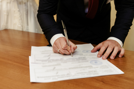happy gorgeous bride and stylish groom signing official document wedding register, emotional moment, ceremonyの写真素材