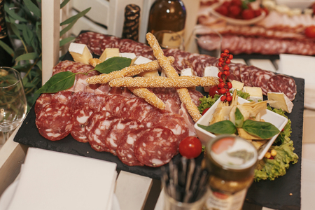 delicious meat plate on wedding reception. table with salami, bacon, prosciutto and smoked meat,basil and bread in restaurant. luxury catering. italian cuisineの写真素材