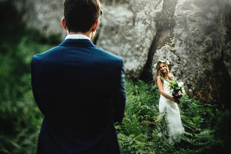 stylish boho bride holding and elegant happy groom on background of rocks in mountainsの写真素材
