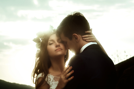 luxury happy bride and stylish groom hugging each other with tender on background of  sunny sky in amazing mountainsの写真素材
