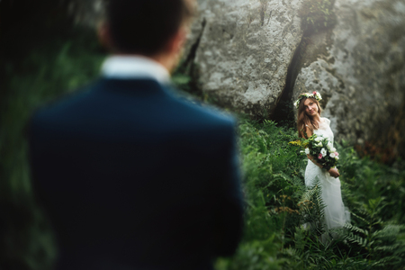 stylish boho bride holding and elegant happy groom on background of rocks in mountainsの写真素材