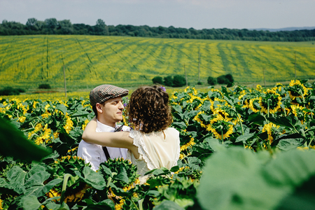 beautiful gorgeous bride and stylish handsome groom, rustic couple in a sunflower sunny fieldの写真素材